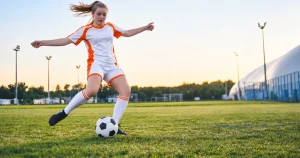 Female soccer player kicking ball on outdoor field