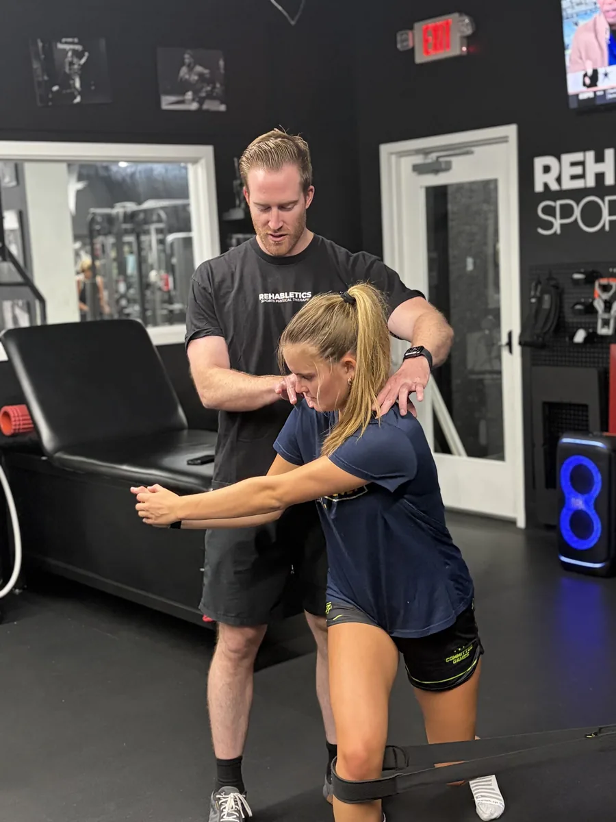 Dr. Erik Bonn correcting an athlete's form during a banded rotation exercise