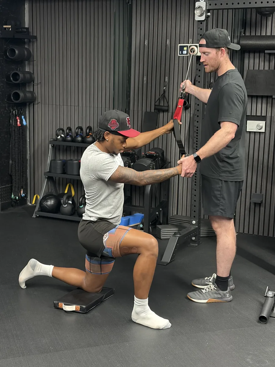 Dr. Erik Bonn coaching an athlete through cable training in a half-kneeling position