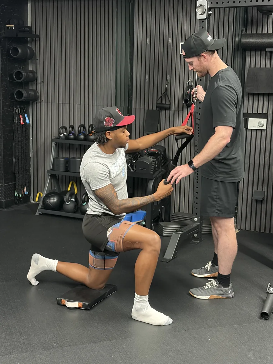 Dr. Erik Bonn setting up an athlete for a half-kneeling cable exercise