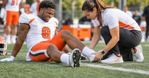 Football player holding his ankle on the field after a sprain