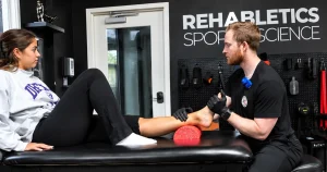 Sports physical therapist assessing an athlete's injured ankle at a Cherry Hill clinic